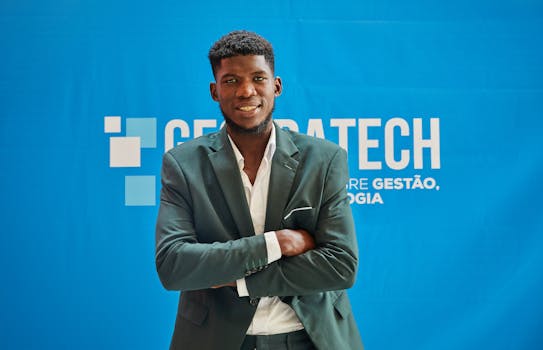 Businessman in suit smiling confidently with arms crossed at a technology event.