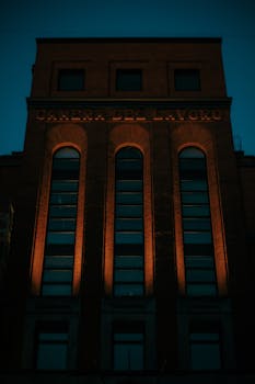 A tall brick building with arched windows illuminated at night, showcasing architectural elegance.
