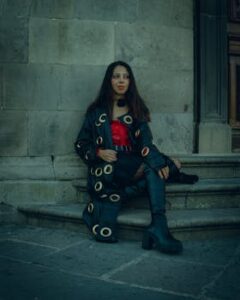 A woman in gothic fashion sitting on stone steps in Puebla, Mexico, exuding a bold urban style.