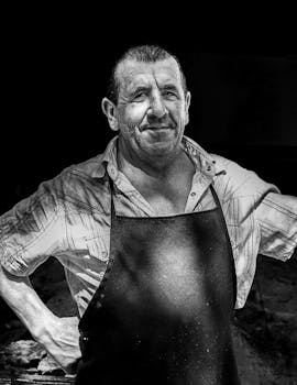 Black and white portrait of a man in an apron, outdoors in Chascomús, Argentina.