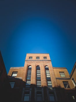 Low-angle view of an office building under a clear blue sky with modern architectural features.