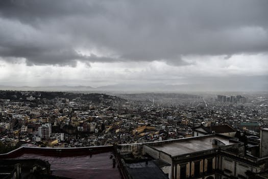 Moody cityscape of Naples under a cloudy sky, capturing the urban sprawl and architecture.