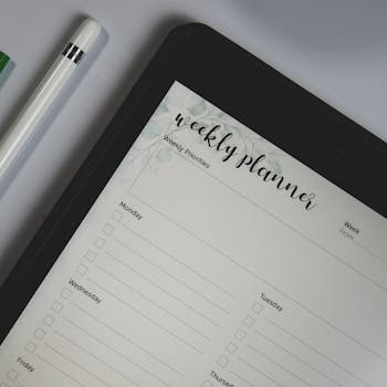Top view of a digital tablet with weekly planner layout and stylus pen, ideal for organization.